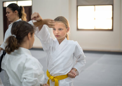 Caucasian teenage kids in kimono practicing karate in a sports gym. Martial arts training session