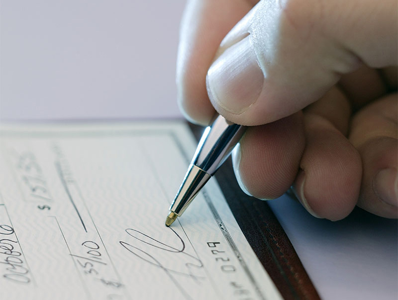 A person's hand signing a check.